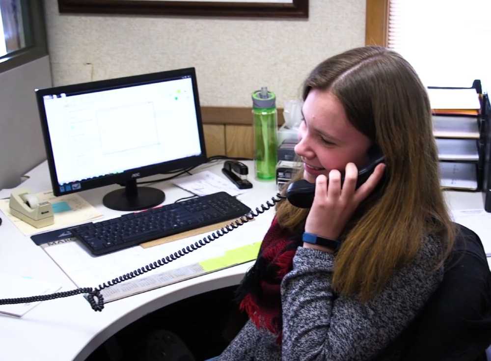 Young woman on the phone at her office desk with a computer and documents.